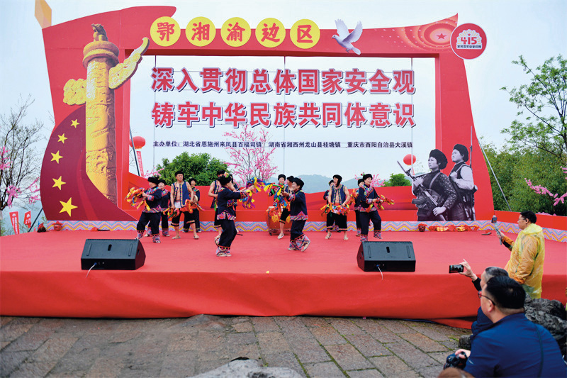 2023年4月15日,在百福司镇兴安村“一脚踏三省”公园里,来凤县、酉阳县、龙山县政府共同举办普法宣传活动,三县土苗儿女在活动的开场仪式上载歌载舞(来凤县司法局 供图).jpg