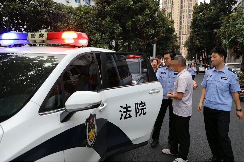 图9为执行干警将被执行人押上警车.jpg 图9为执行干警将被执行人押上警车.jpg