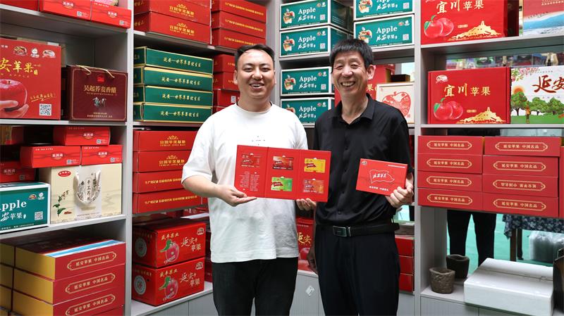 呼永祥、呼鹏父子介绍新推出的“延安苹果 中国好礼”苹果提货卡。_proc.jpg