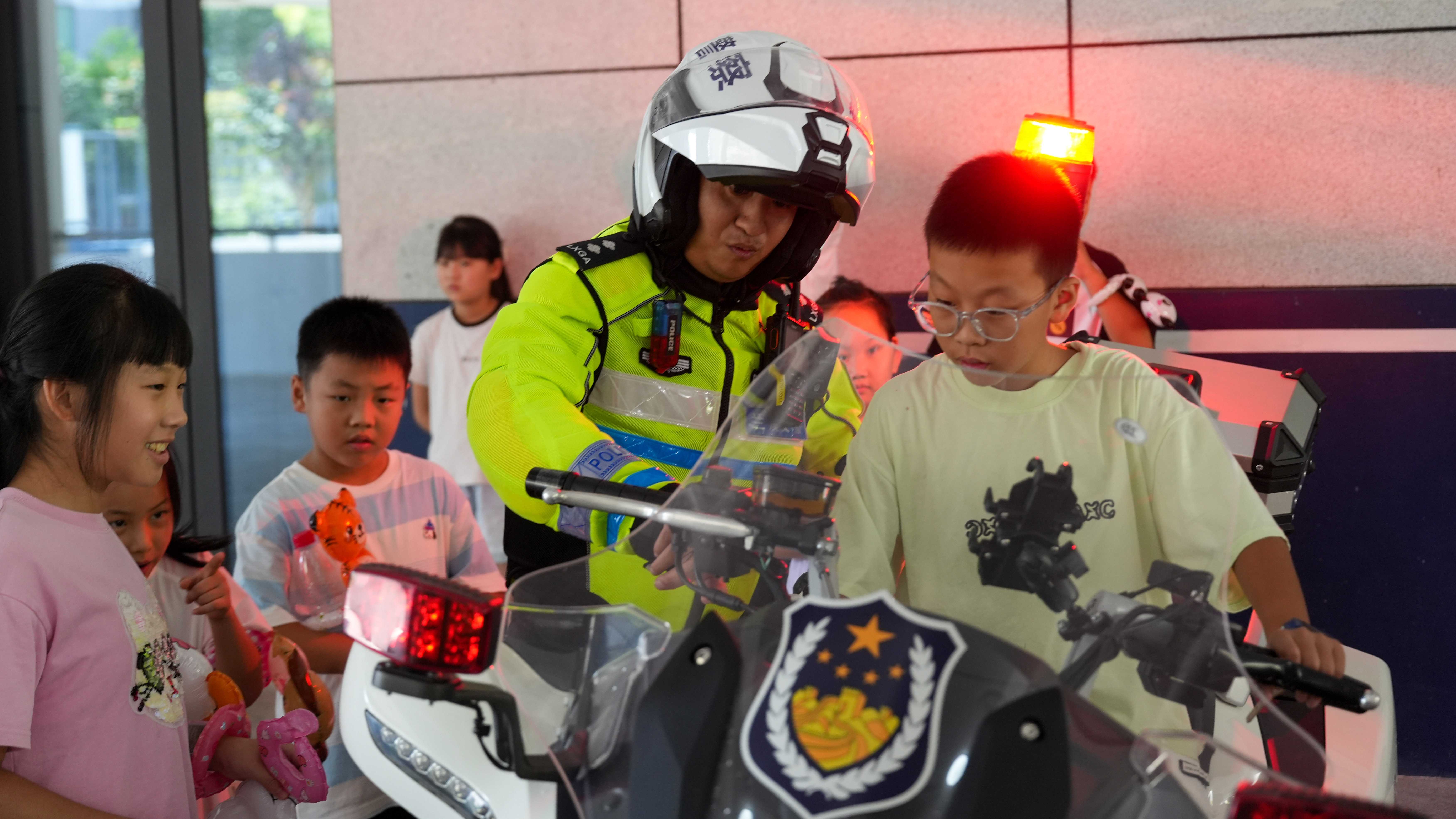 图为8月26日上午，浙江省兰溪市公安局交警大队民警带警娃们体验铁骑摩托车，感受高温下摩托车的温度。.JPG