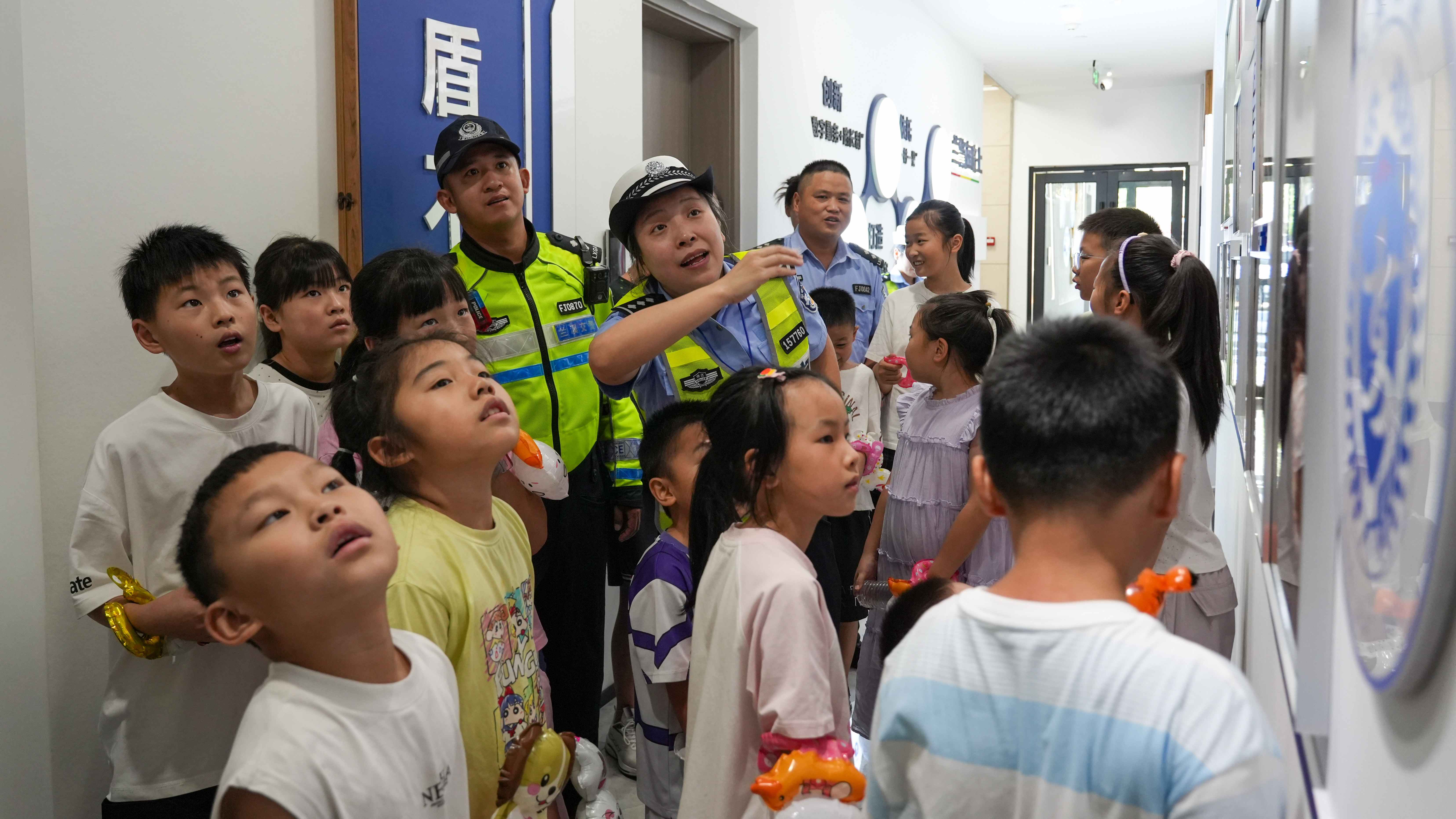 图为8月26日上午，浙江省兰溪市公安局交警大队民警向警娃讲解着警营文化墙上一幕幕暖心警事。.JPG