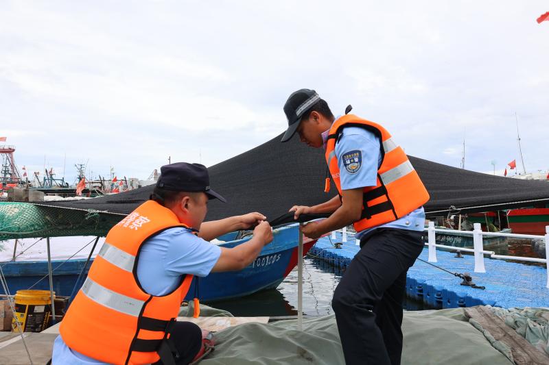 6月12日，图为港门海岸派出所民警帮助小渔船做好防风措施.JPG