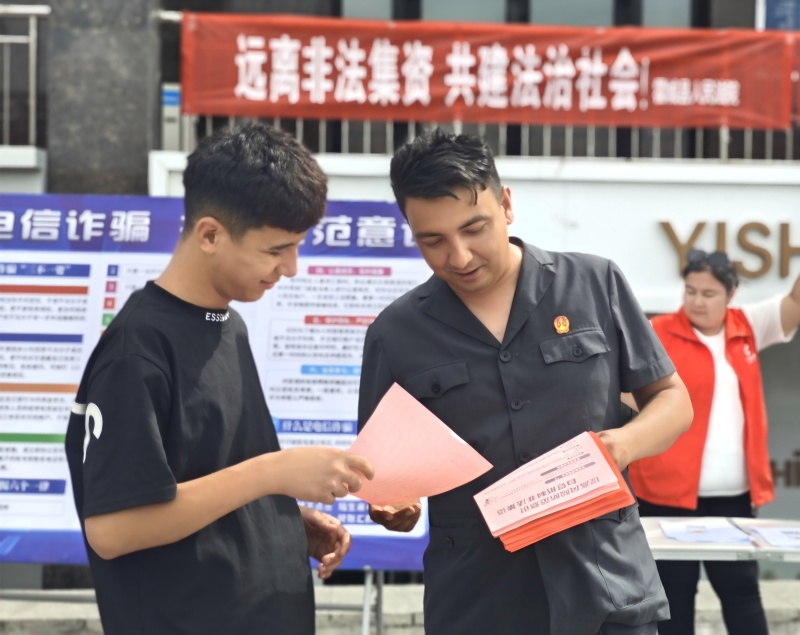 图说：霍城县人民法院刑事审判庭干警向过往群众发放法制宣传单，并解释非法集资相关内容(1).jpg