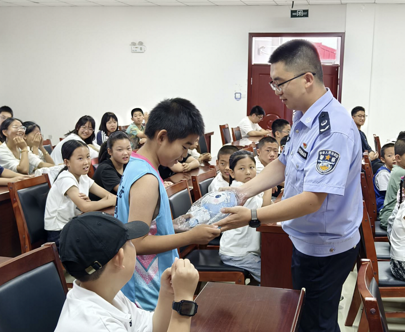 图为：司法所干警为答对问题的学生发放“法治白杨IP形象玩偶”.png