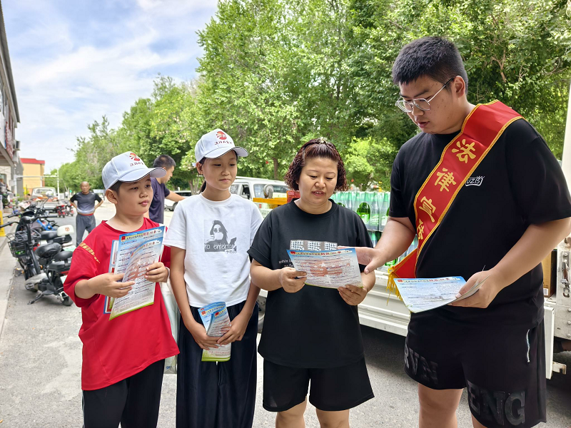 图为：返乡大学生与小小法治宣讲员开展法治宣传.png