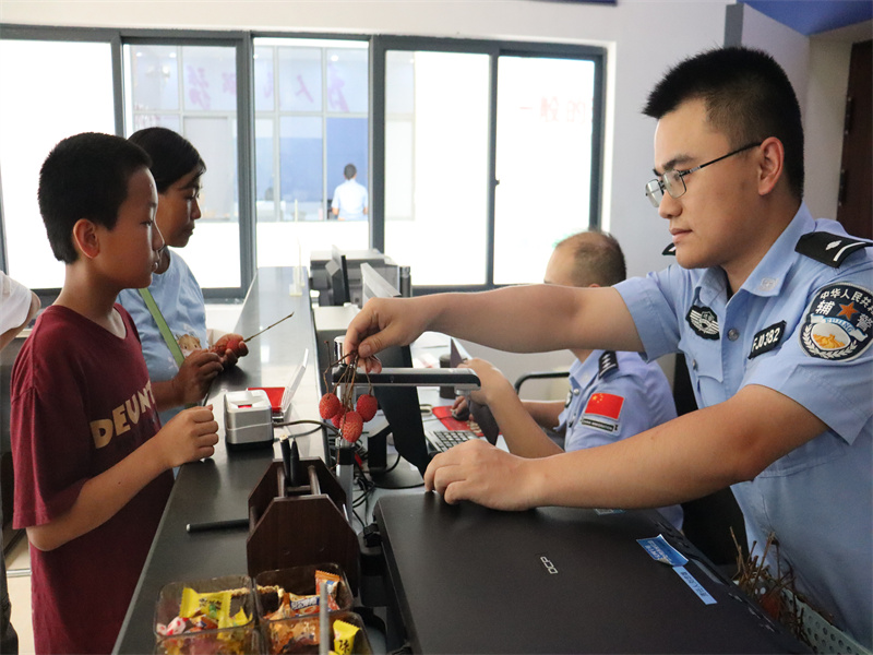 辅警为前来办事的群众分发荔枝.JPG